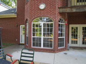 An outside view of beautiful windows in front of a brick house